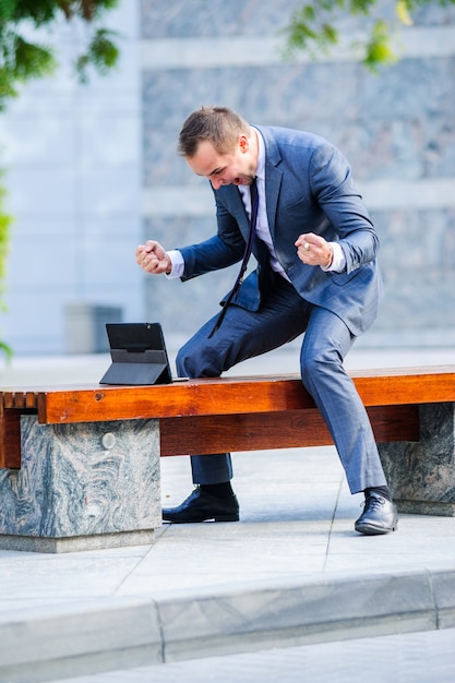 L'homme d'affaires Yang travaille avec une tablette à l'extérieur.