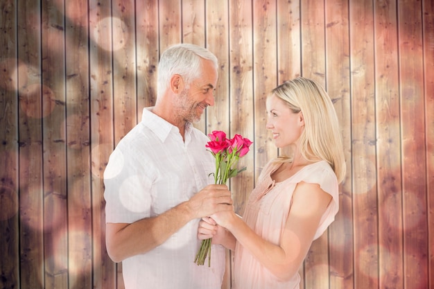 Homme affectueux offrant à son partenaire des roses contre des cercles de lumière sur fond noir