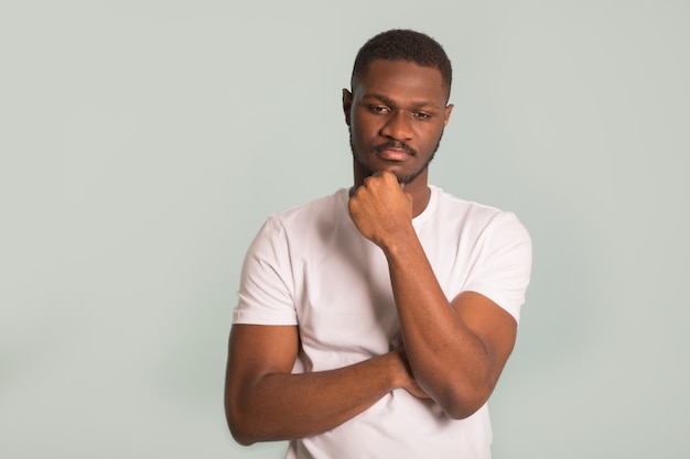 Homme africain adulte dans un T-shirt blanc avec un visage triste sur fond bleu