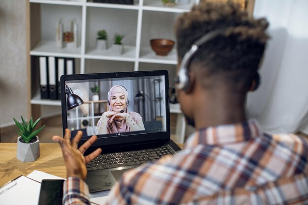 Homme africain ayant un chat vidéo sur ordinateur portable avec une femme musulmane