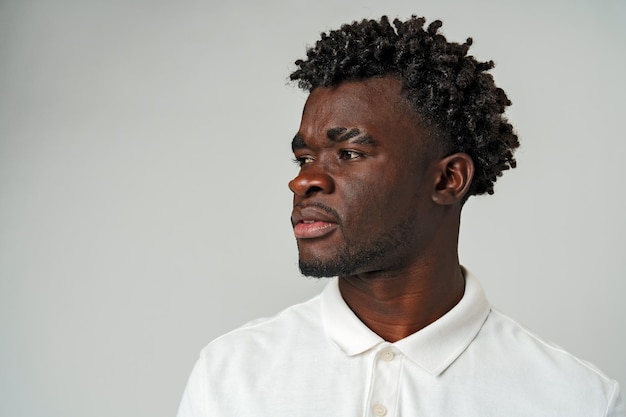 Un homme africain en chemise blanche regardant de côté.