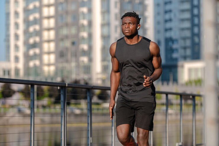 Photo un homme africain confiant en vêtements de sport qui a l'air concentré en faisant du jogging à l'extérieur