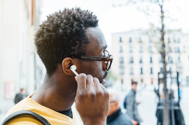 Homme africain, écouter de la musique avec des écouteurs. Il met l'écouteur est son oreille.