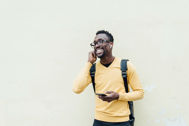 Homme africain, écouter de la musique avec des écouteurs. Il met l'écouteur est son oreille.