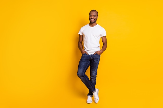 homme africain heureux et confiant posant sur un mur jaune