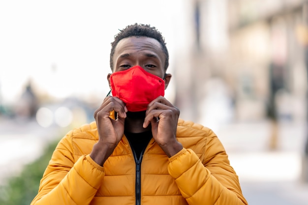 Homme africain mettant sur un masque rouge avec fond de ville floue