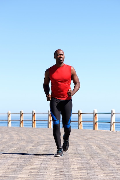 Homme africain musclé qui court sur la promenade de bord de mer