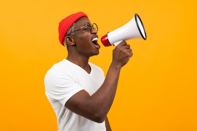 Homme africain noir parle dans un mégaphone sur jaune isolé