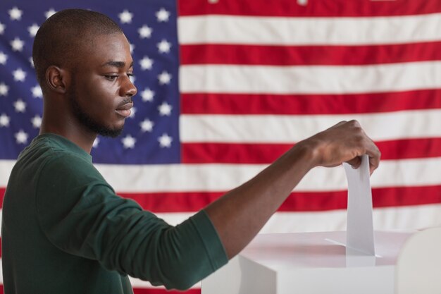 Homme africain sérieux mettant la lettre dans la boîte pendant le vote