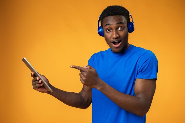 Homme africain souriant utilisant une tablette numérique sur fond jaune