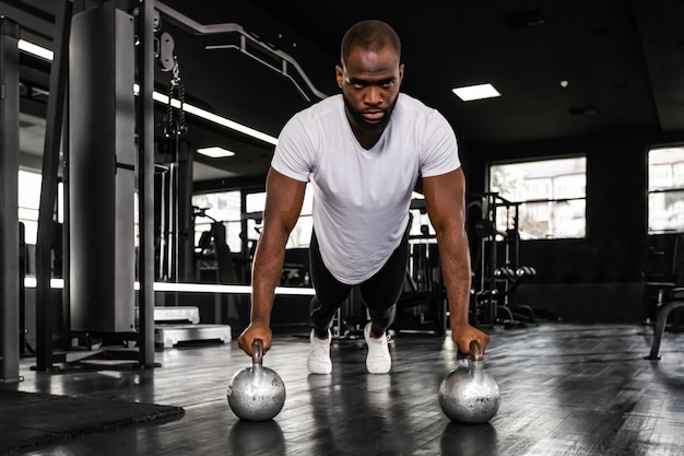 Homme africain sportif faisant des pompes dans une salle de sport