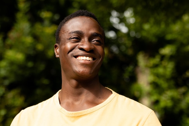 Homme afro-américain adulte mi souriant tout en regardant loin contre les plantes