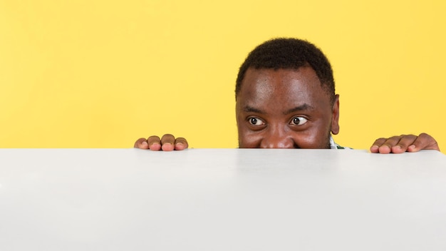 Homme afro-américain affamé regardant une table vide sur fond jaune