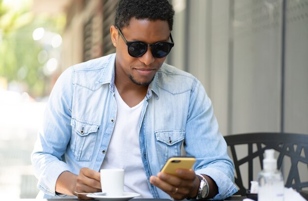 Homme afro-américain à l'aide de son téléphone portable alors qu'il était assis dans un café.