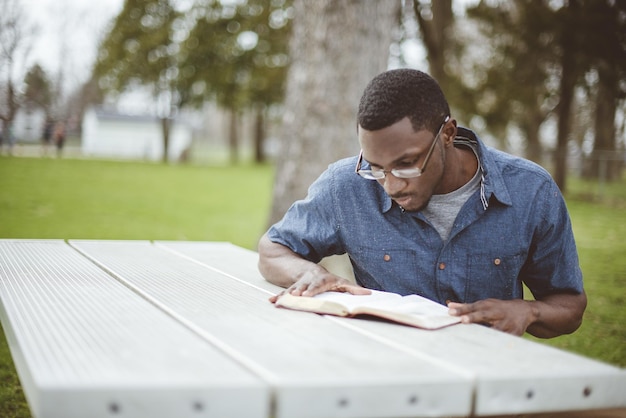 Homme afro-américain assis à une table et lisant la Bible