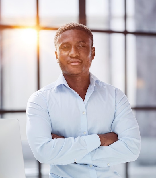 homme afro-américain assis sur une table et posant les mains jointes dans son bureau