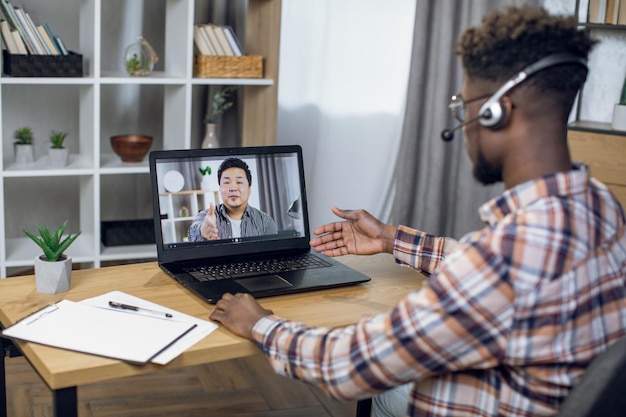 Homme afro-américain ayant un appel vidéo avec un collègue asiatique