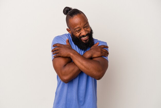 Homme afro-américain avec barbe isolé sur des câlins de mur rose, souriant insouciant et heureux.