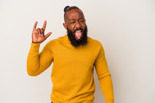 Homme afro-américain avec barbe isolé sur fond rose montrant un geste rock avec les doigts