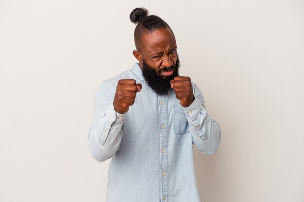 Homme afro-américain avec barbe isolé sur fond rose montrant le poing à la caméra, expression faciale agressive.