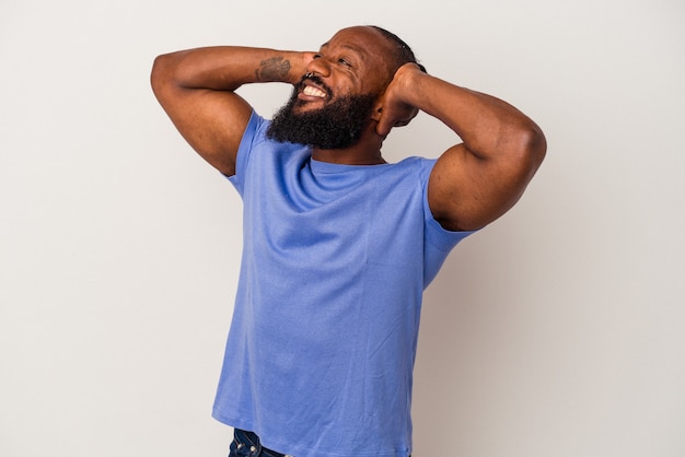 Homme afro-américain avec barbe isolé sur mur rose se sentant confiant, les mains derrière la tête.