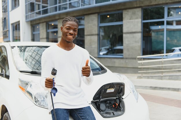 Homme afro-américain chargeant sa voiture électrique.