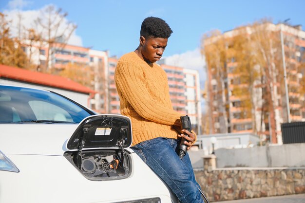 Homme afro-américain chargeant sa voiture électrique.