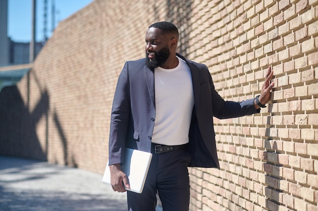 Un homme afro-américain en costume debout près du mur de briques