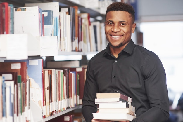 Homme afro-américain dans la bibliothèque à la recherche d'informations dans les livres