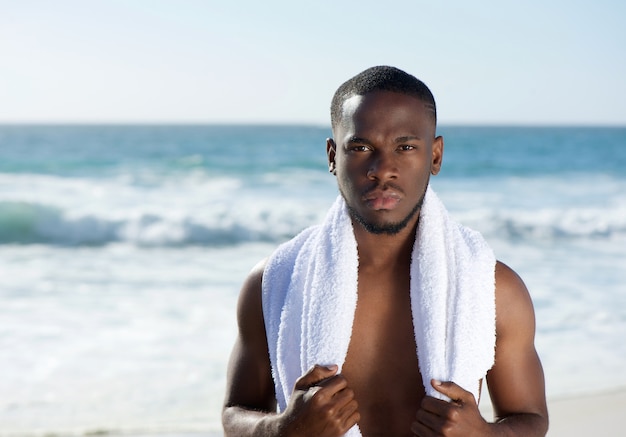 Homme afro-américain debout à la plage avec une serviette