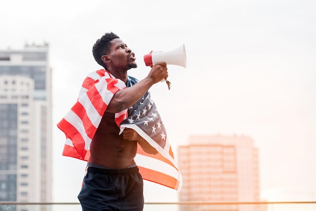 Homme afro-américain avec drapeau américain criant dans un mégaphone pour protester contre la vie noire metter