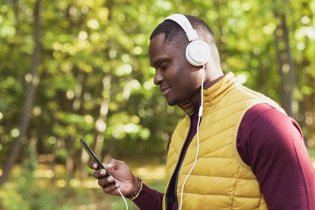 Un homme afro-américain écoute de la musique dans l'espace de copie du parc de printemps et place pour l'application de gadget publicitaire
