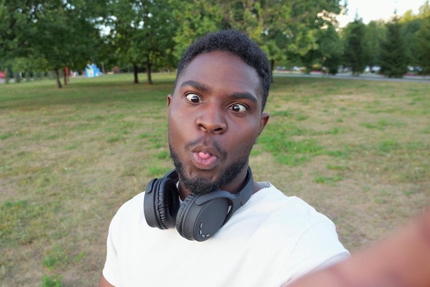 Un homme afro-américain fait des selfies en grimaçant contre le parc