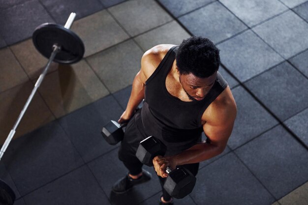 Un homme afro-américain fort en vêtements sportifs a une journée d'entraînement dans la salle de sport