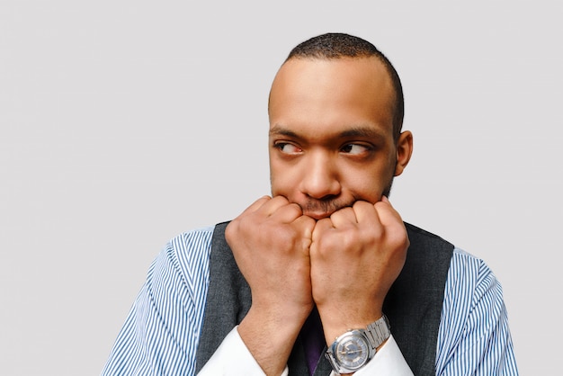 Homme afro-américain horrifié choqué couvrant la bouche avec les mains se sentir effrayé sur mur gris