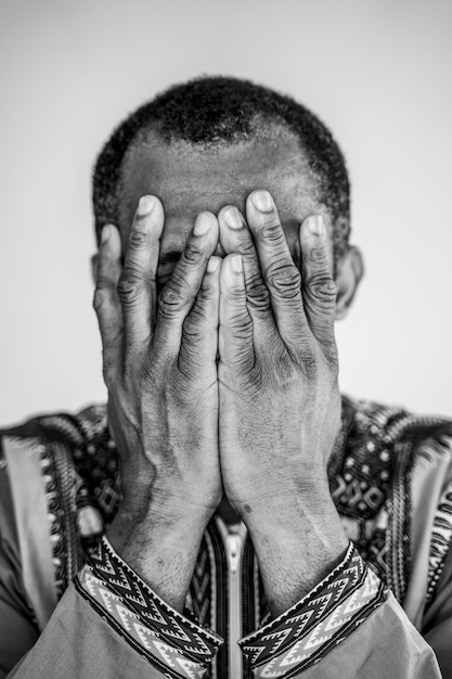 Homme afro-américain isolé couvrant sa bouche avec les mains. Symptômes de dépression et de tristesse.