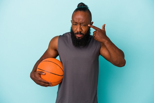 Homme Afro-américain Jouant Au Basket-ball Isolé Sur Fond Bleu Montrant Un Geste De Déception Avec L'index.