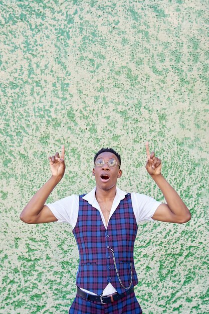 Homme afro-américain avec des lunettes pointant vers l'extérieur avec le doigt isolé sur fond vert