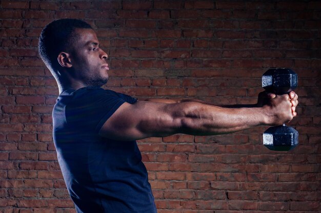 Homme afro-américain musclé faisant de l'exercice avec haltère