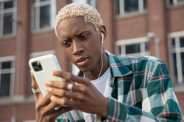 Homme afro-américain pensif tenant un téléphone portable lisant un message texte, communication en ligne