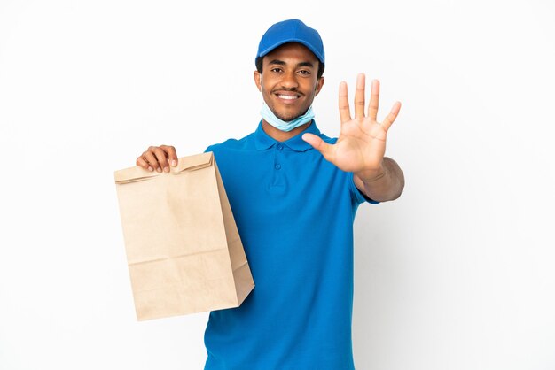 Homme afro-américain prenant un sac de nourriture à emporter isolé sur fond blanc comptant cinq avec les doigts