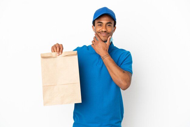 Homme afro-américain prenant un sac de nourriture à emporter isolé sur fond blanc pensant