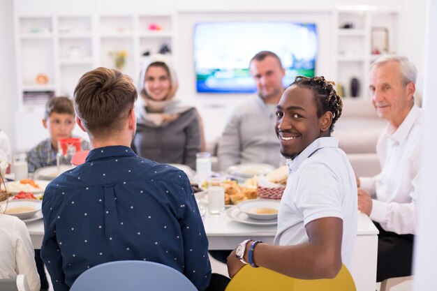 Photo homme afro-américain profitant d'un dîner iftar avec une famille musulmane multiethnique moderne lors d'une fête du ramadan à la maison