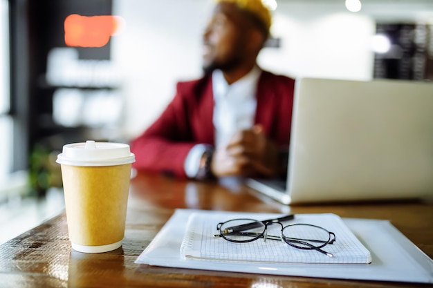 Un homme afro-américain reçoit une éducation en ligne et boit du café pour aller dans une tasse écologique en papier