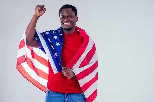 Homme afro-américain regardant la caméra et tenant fièrement le drapeau américain au studio