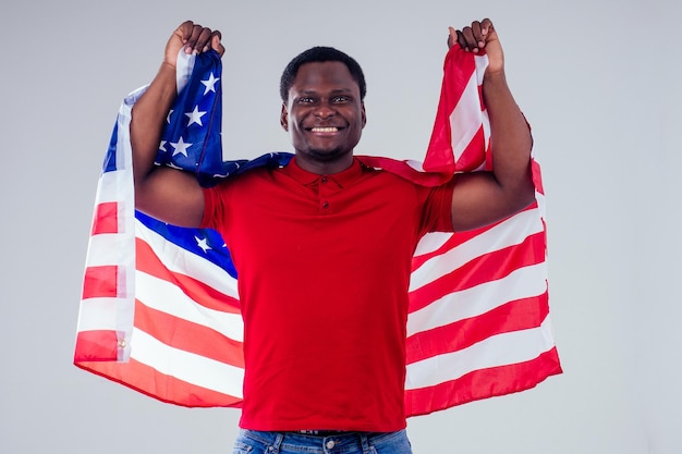 Homme afro-américain regardant la caméra et tenant fièrement le drapeau américain au studio