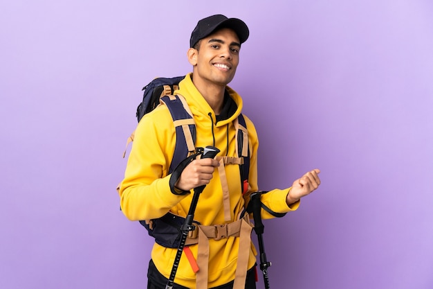 Photo homme afro-américain avec sac à dos et bâtons de randonnée pointant vers l'arrière