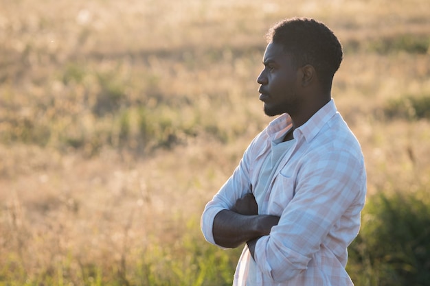 L'homme d'afro-américain se tient contre la plantation mûre de blé