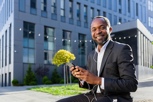 Un homme afro-américain senior un homme d'affaires en costume est assis à l'extérieur d'un centre de bureau portant