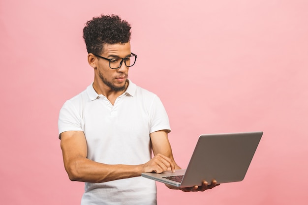 Homme Afro-américain Sérieux Réfléchi Avec Ordinateur Portable Isolé Sur Fond Rose